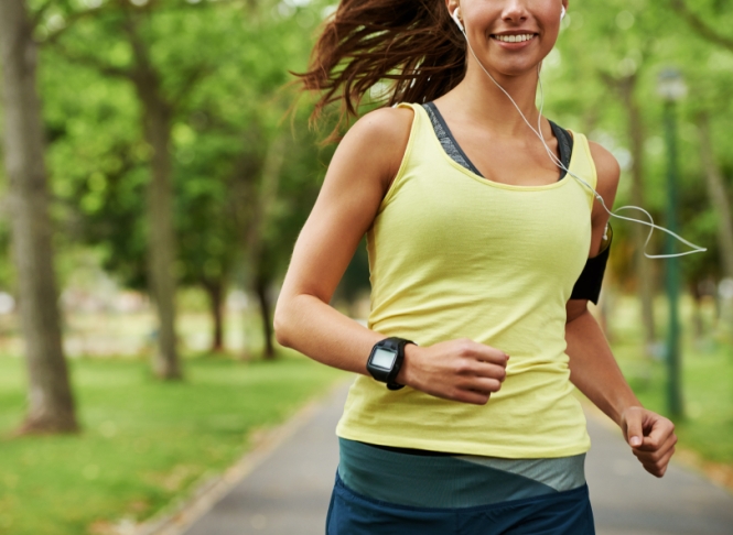 Cropped shot of a sporty young woman listening to music while running outdoors